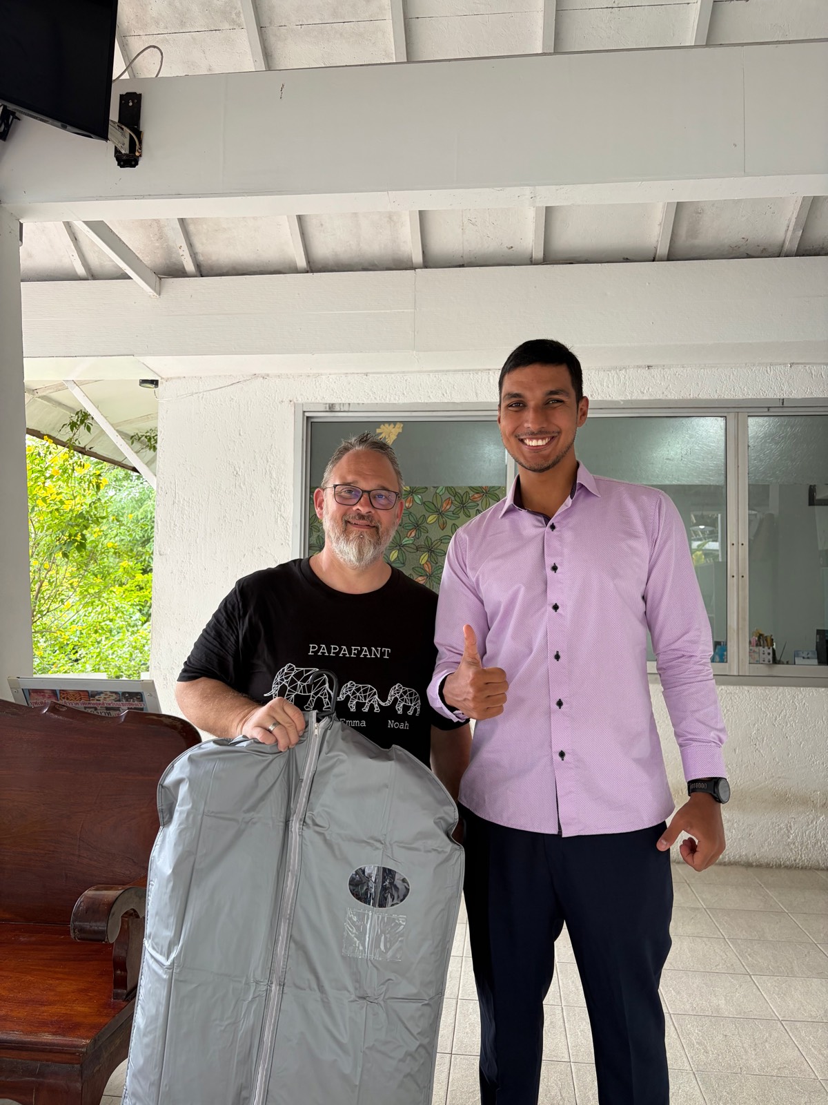 Client receiving his finished suit in a garment bag at his hotel